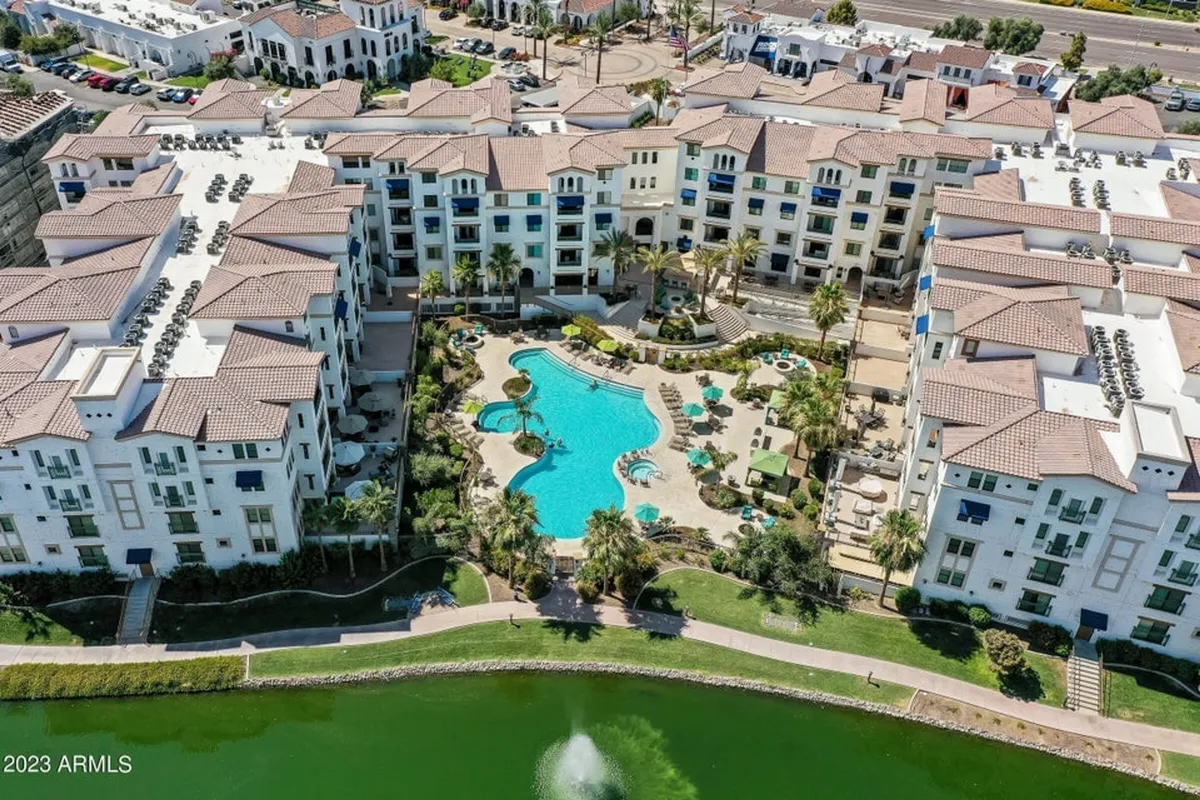 An exterior shot featuring a sparkling swimming pool surrounded by lush landscaping and residential buildings, with inviting pathways and outdoor spaces suggesting leisure and social opportunities.
