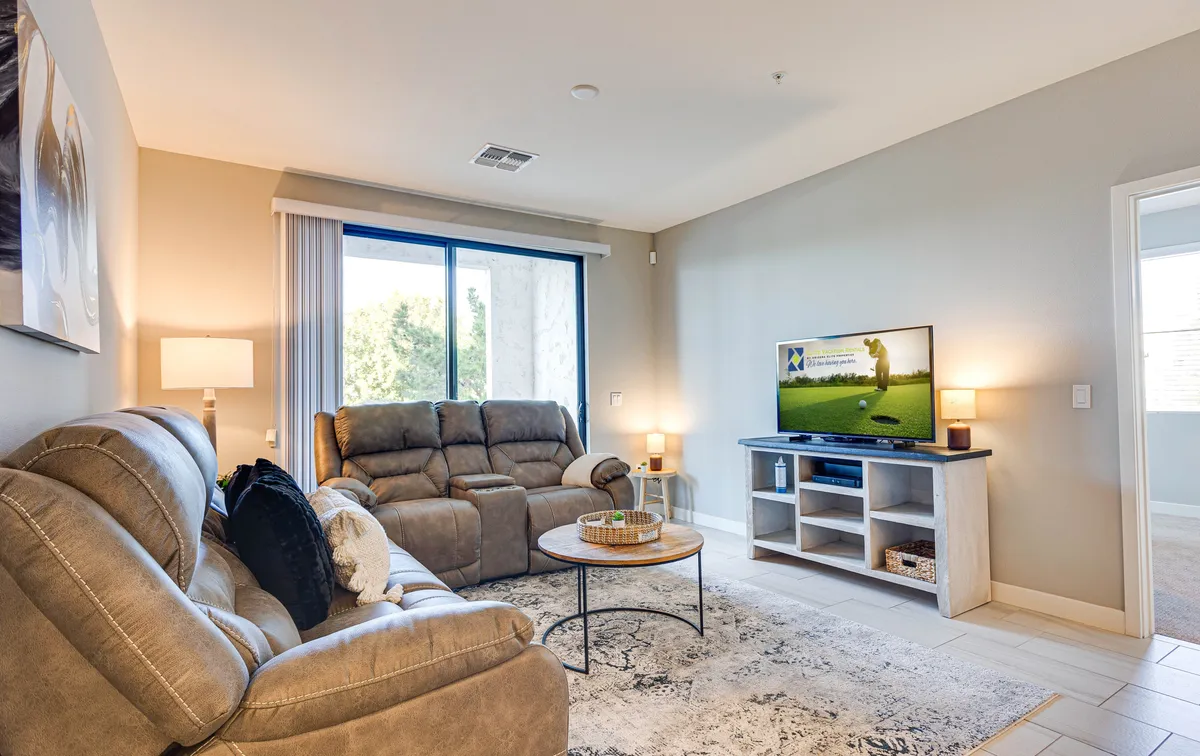 This image features a living space with comfortable recliners facing a large television, with a coffee table positioned centrally. The mood is inviting and comfortable, ideal for relaxation and entertainment. It highlights the living room's potential for cozy movie nights and social gatherings.