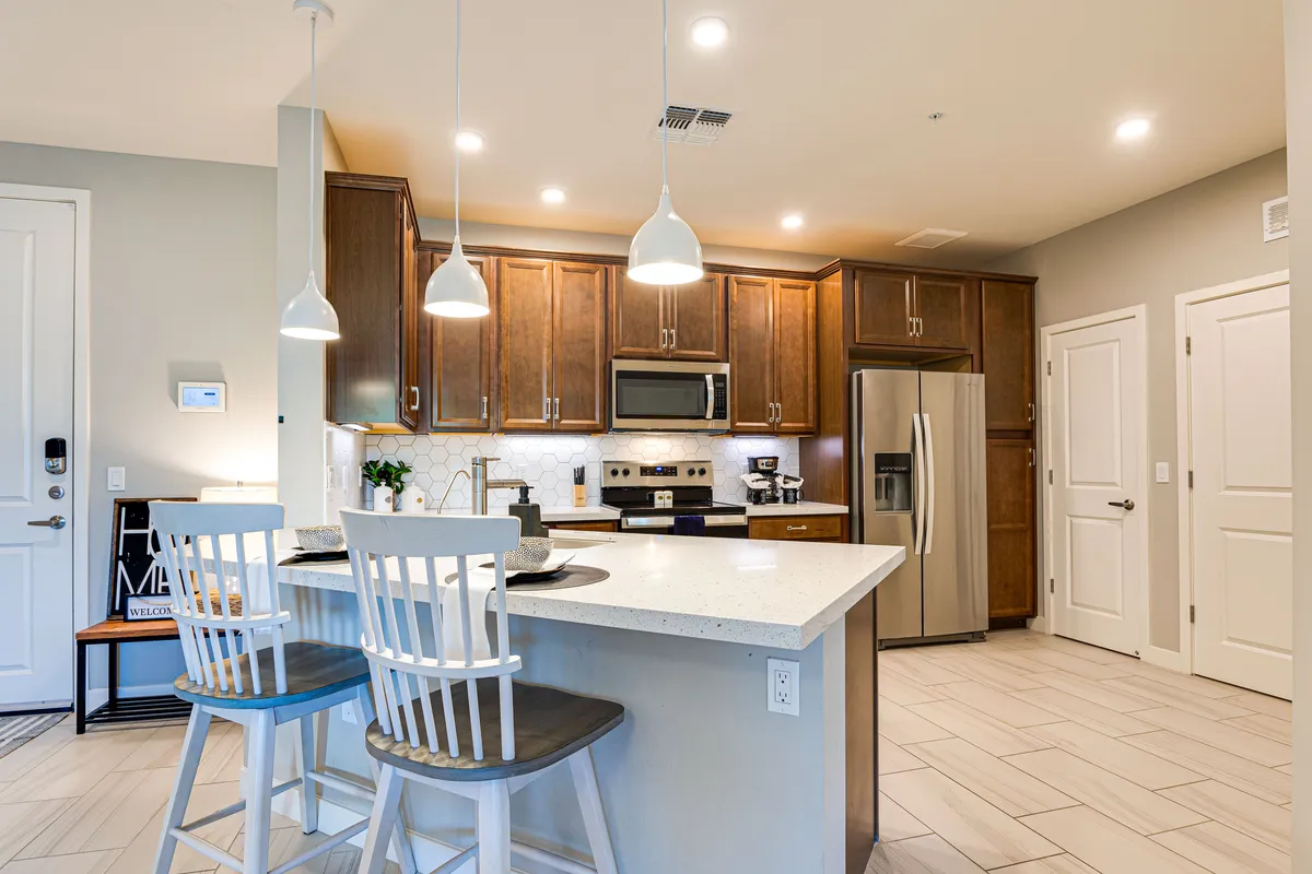 The kitchen area is highlighted with a prominent kitchen island, stainless steel appliances, wooden cabinetry, and contemporary pendant lighting. The layout is modern and functional, inviting guests to cook, dine, and entertain.